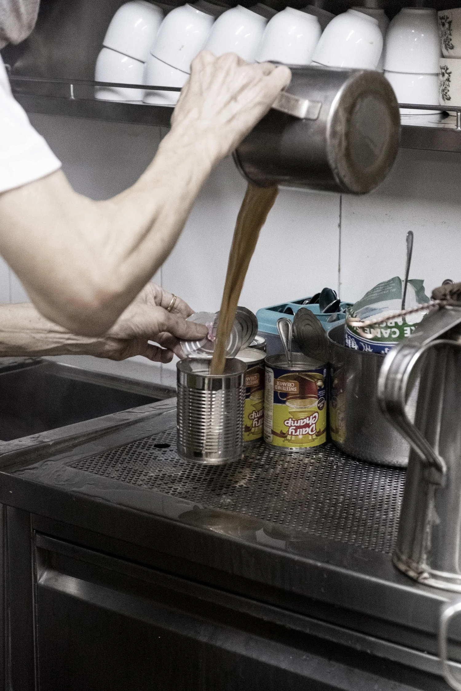 Coffee being poured into a milk tin